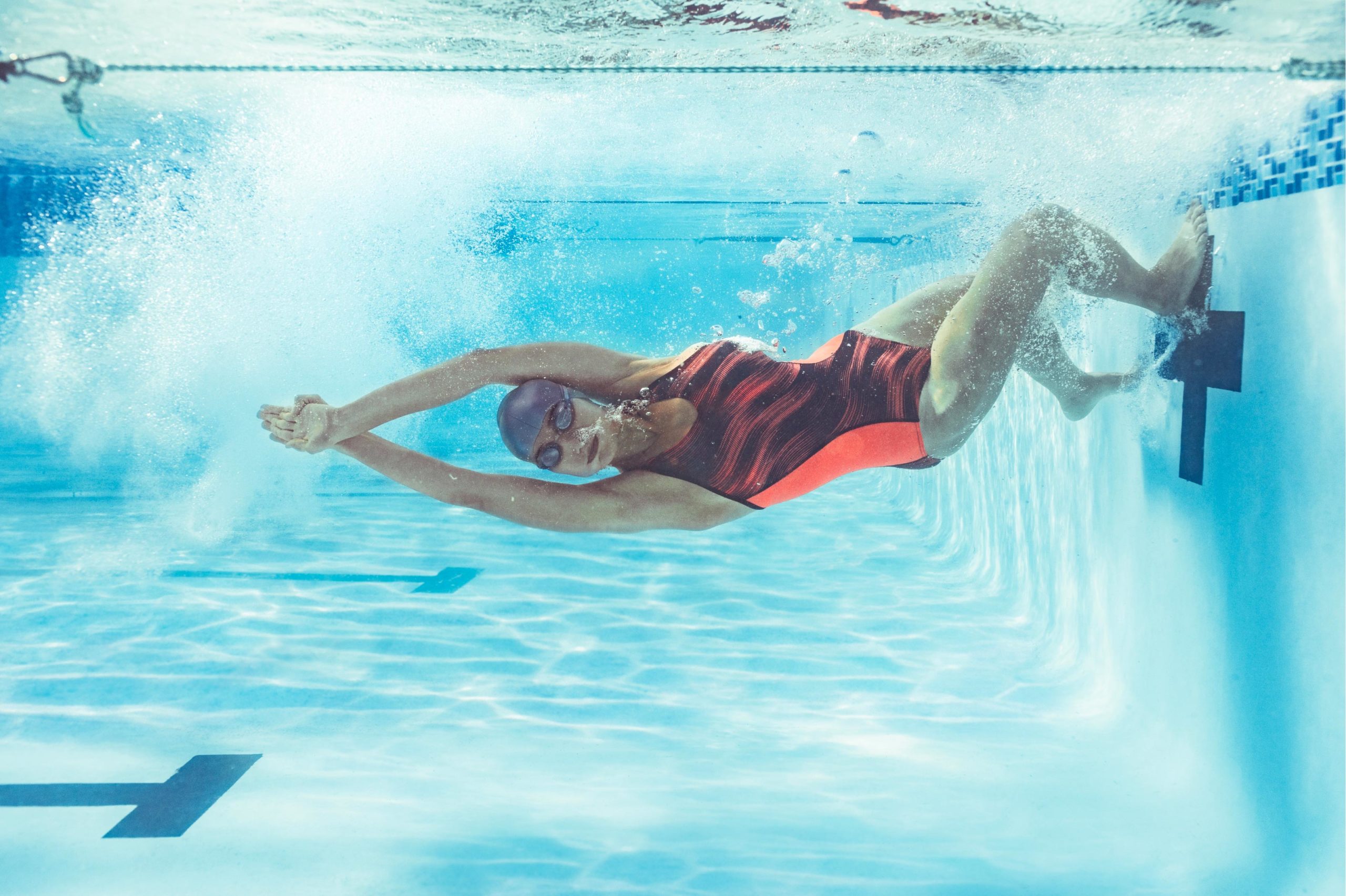 Photo d'une femme qui prend appuie sur le bord de la piscine pour relancer sa nage